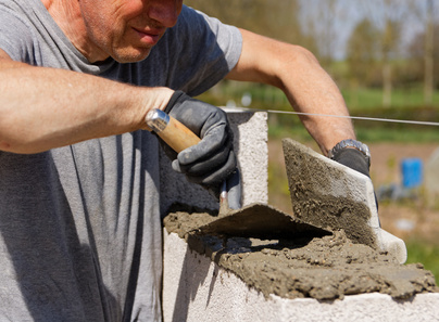 Etalement du ciment pour la construction d’un mursite internet pour maçon